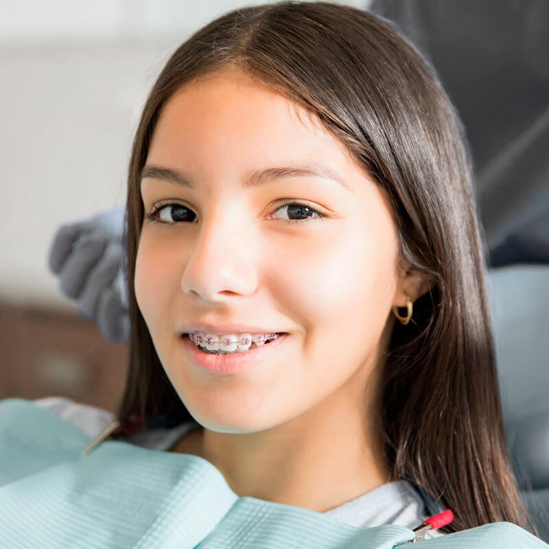 Teen girl with metal braces smiling in the dental chair