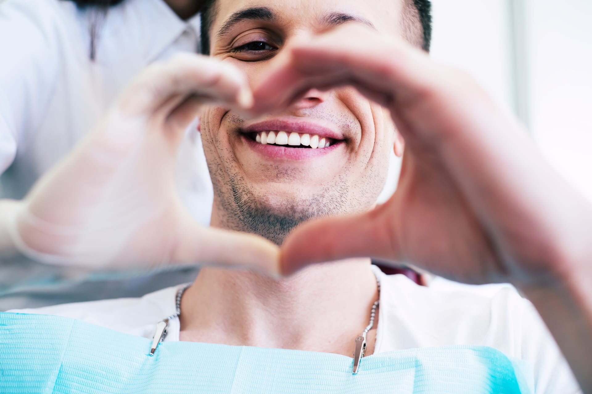 Patient in the dental chair making a heart shape with their hands