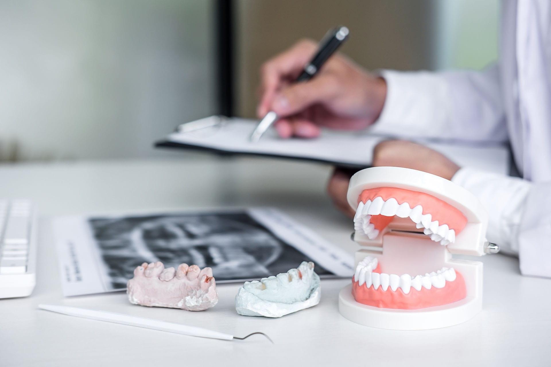 Orthodontist taking notes beside a dental model and an X-ray
