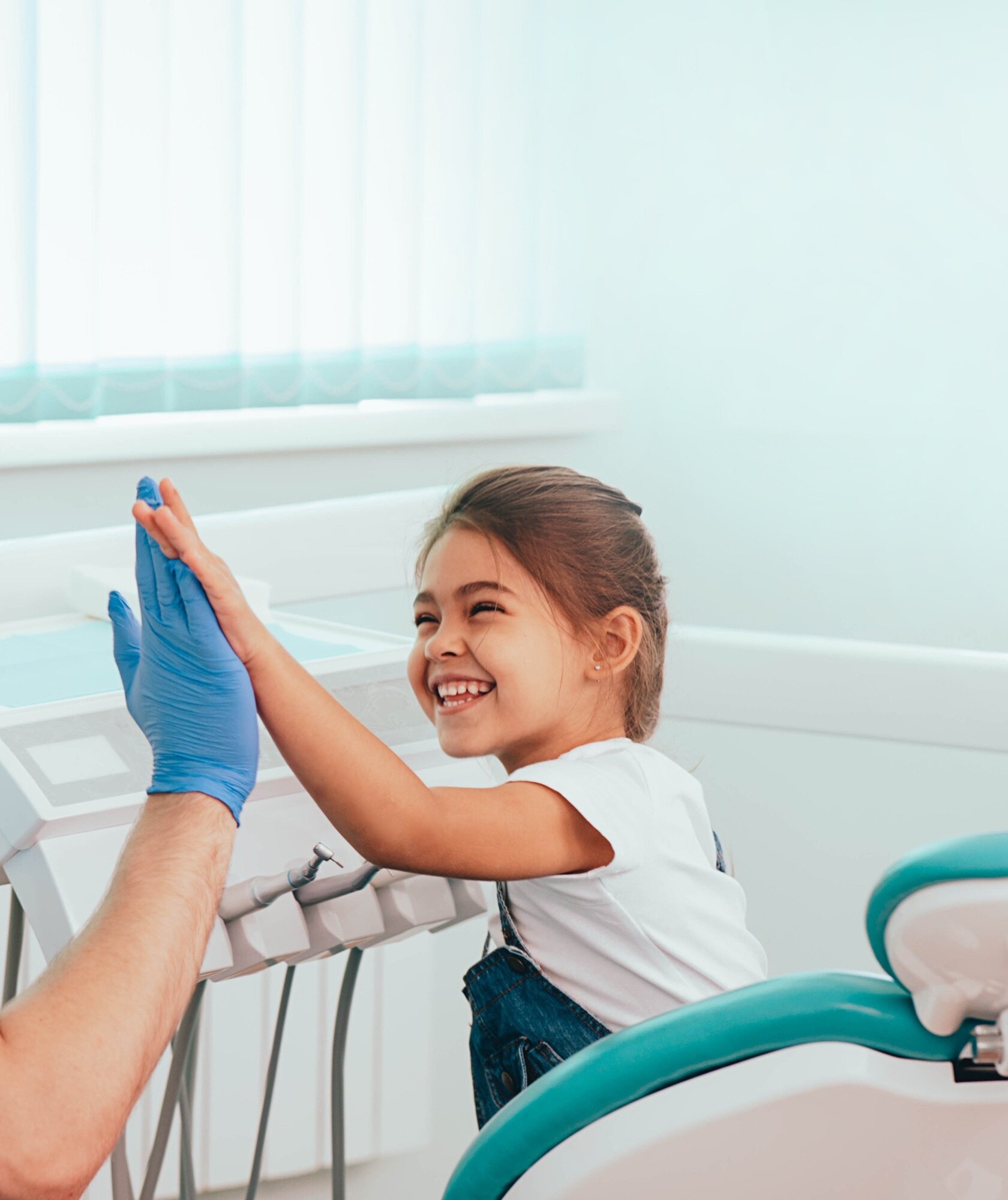Young patient high-fiving her orthodontist after an appointment
