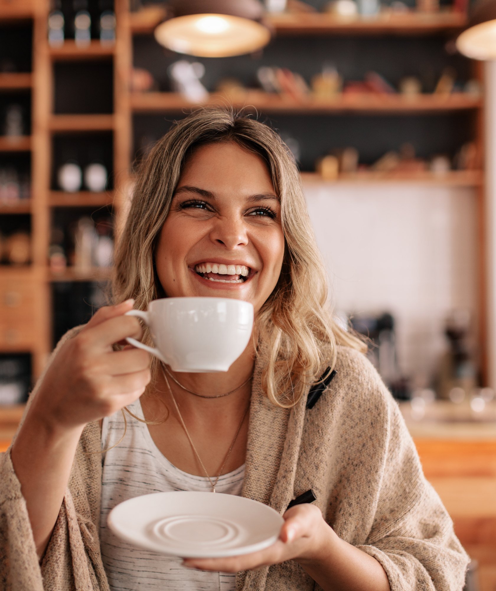 Smiling woman enjoying coffee at a cafe after orthodontic treatment