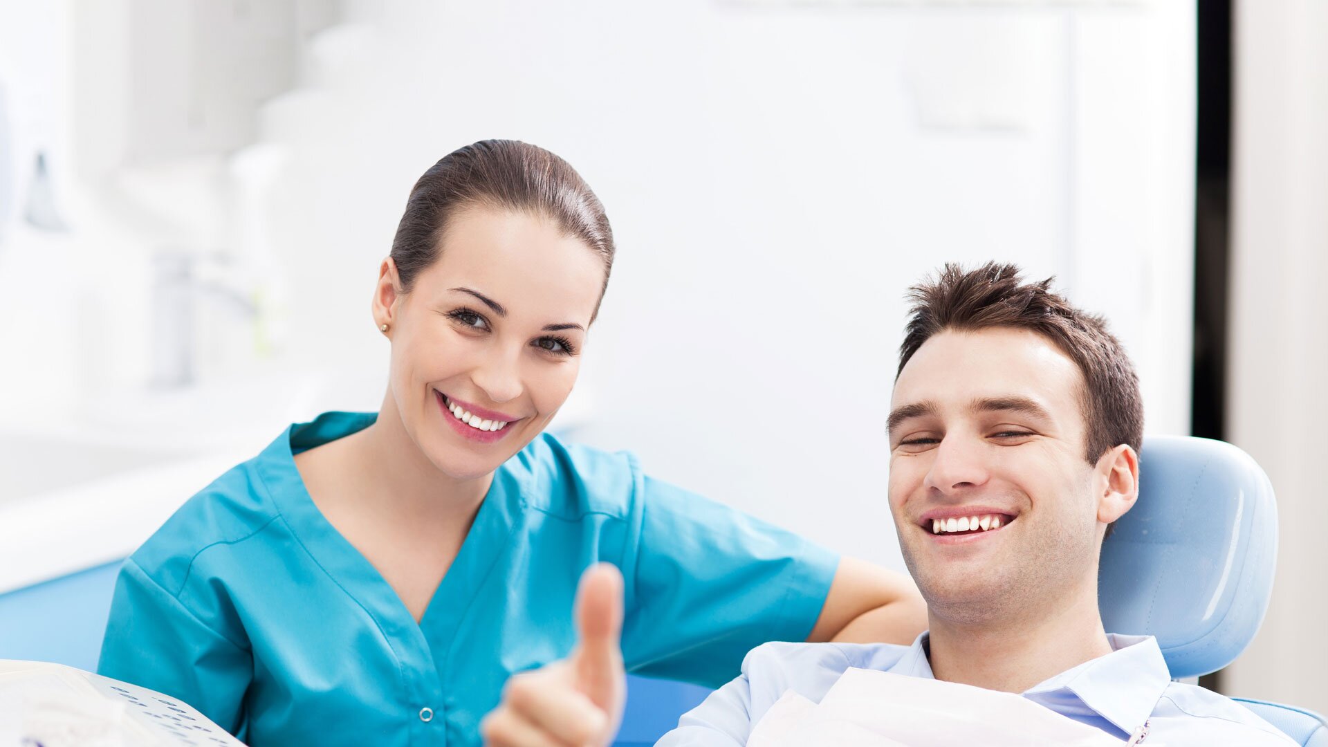 Smiling patient and dental assistant giving a thumbs up